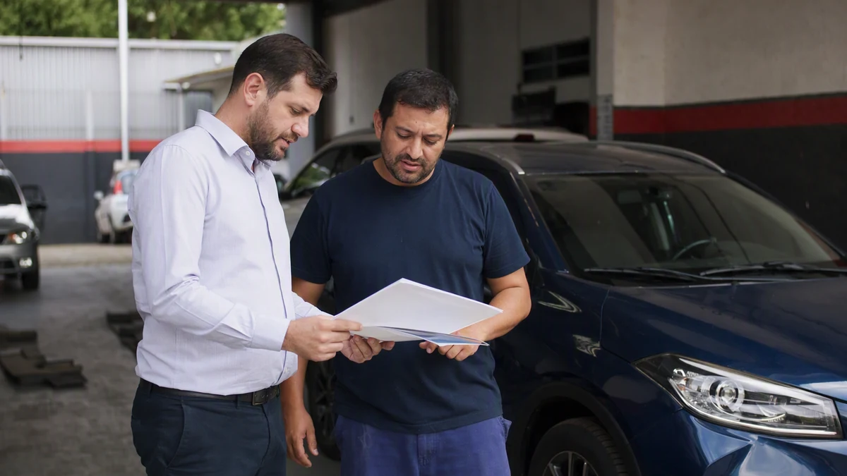 Seguro de carro francês: consultor e cliente analisam documentos no pátio