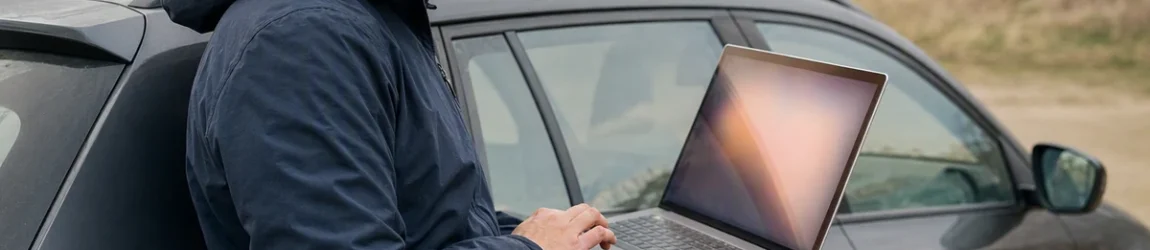 Como consultar recall do meu carro: pessoa consulta site em laptop ao lado do carro